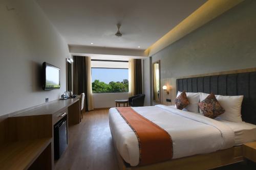 钱德加尔HOTEL KLG ALTORIA的酒店客房设有一张床和一个大窗户
