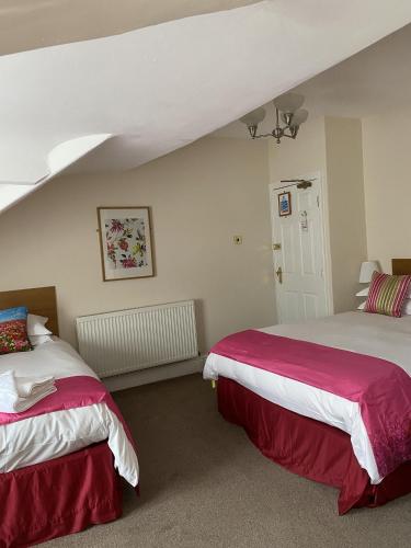 布莱克浦罗斯登之家酒店的一间卧室配有两张红色和白色床单