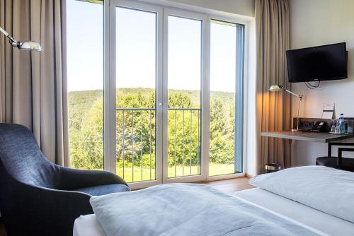 BrombachtalBURGHOF - DAS HOTEL的酒店客房设有一张床和一个大窗户
