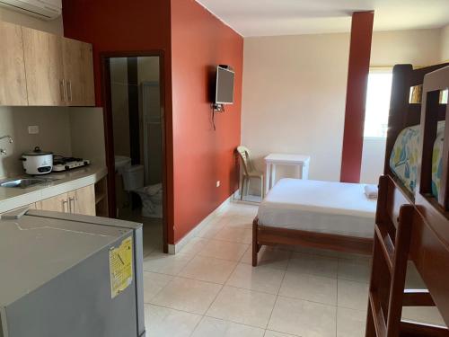 曼塔考斯塔阿祖尔旅馆的一间卧室配有床,厨房配有红色的墙壁