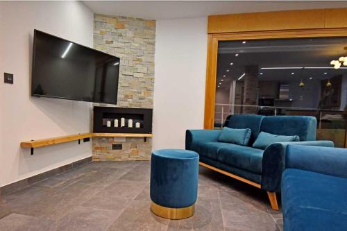 FuentetobaCasa Rural La Cueva del Agua的客厅配有蓝色的沙发和平面电视。