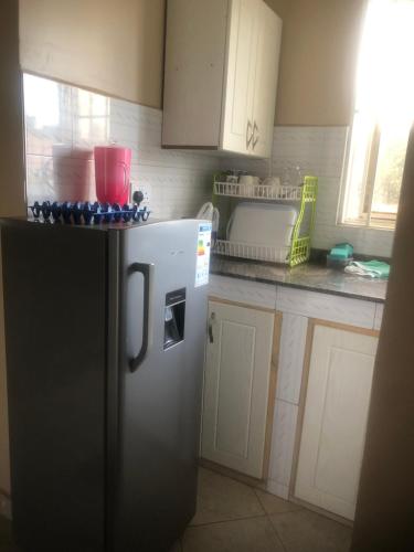 坎帕拉Brooks apartments的厨房配有黑冰箱和白色橱柜。