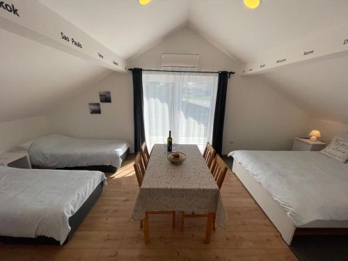 拉科维察VIP Apartments & Room的客房设有两张床、一张桌子和一扇窗户。