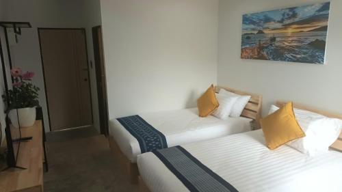 乌隆他尼Hug Udon Hotel的酒店客房设有两张床,墙上挂有绘画作品