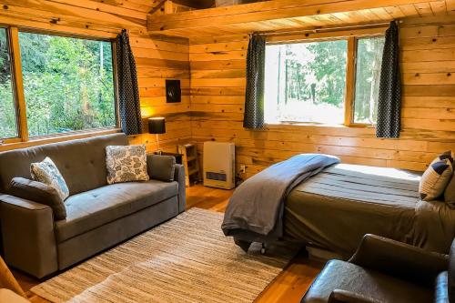 Shelter CoveCove Cabin Retreat的一间卧室配有一张床、一张沙发和窗户。