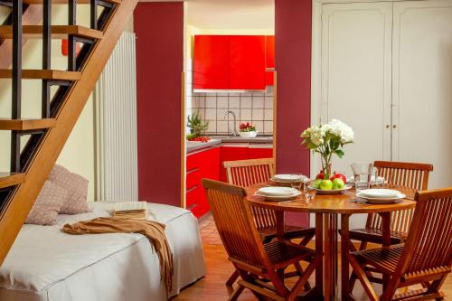罗马波洛公寓酒店的一间带桌子的用餐室和一间带红色橱柜的厨房