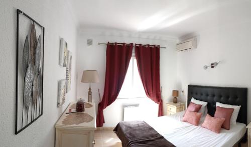 EsteponaLe joyau Andalou的一间卧室配有一张带红色窗帘的床和一扇窗户