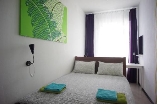 圣彼得堡Vitamin Rooms的一间卧室配有一张挂着绿色画作的床铺。