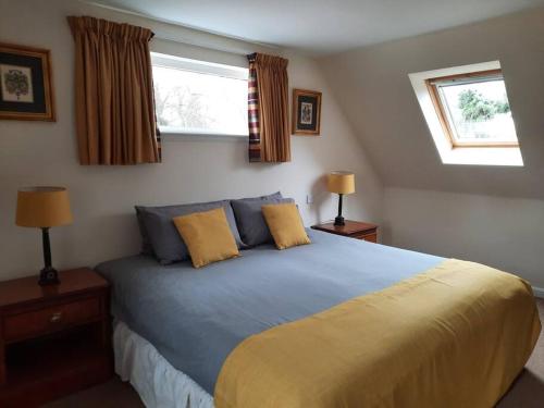 布莱尔高里Fir Tree Cottage的一间卧室设有一张大床和两个窗户