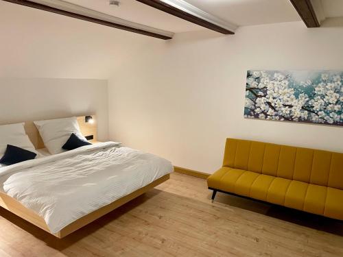 PentlingChalet an der Donau direkt bei Regensburg, 5 Sterne DTV的一间卧室配有一张床和一张黄色的沙发