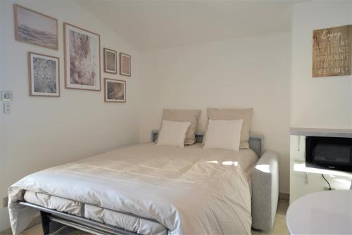 克吕塞耶STUDIO dernier étage avec terrasse - vue montagne的一间卧室配有一张带白色床单的床和一台电视。