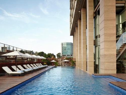 雅加达雅加达门腾辉盛庭国际公寓的酒店游泳池设有躺椅和遮阳伞