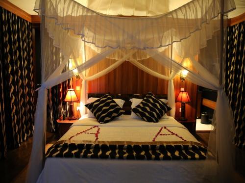塔勒克马赛马拉AA酒店的卧室配有带黑白枕头的天蓬床。