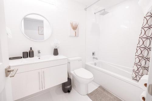 尼亚加拉瀑布Luxury & Comfy Apartment, Mins Drive To All Niagara Falls Attraction的白色的浴室设有卫生间、水槽和浴缸。