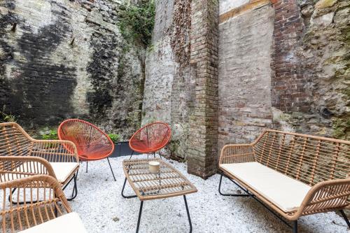 翁弗勒尔L'Atelier d'Eléa - 4 - Terrace - Indus-chic in the heart of Honfleur - 6 P的一组椅子和桌子,旁边是砖墙