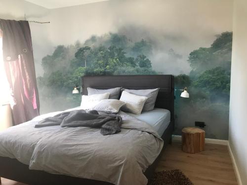 纳尔巴赫Ferienwohnung Piesbach的卧室配有一张壁挂森林壁画的床