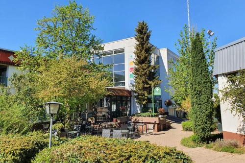 肯钦根Sport Hotel Kenzingen的一座带庭院的建筑,庭院里设有桌子和树木