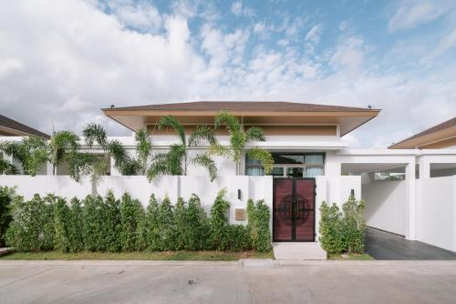 邦涛海滩Villa Alanna Phuket的白色的房子,有围栏和棕榈树