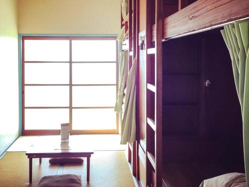宫津市天桥立青年旅舍的客房设有桌子和大窗户。