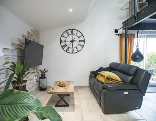 特鲁瓦Loft avec jardin et parking privé的客厅配有沙发和墙上的时钟