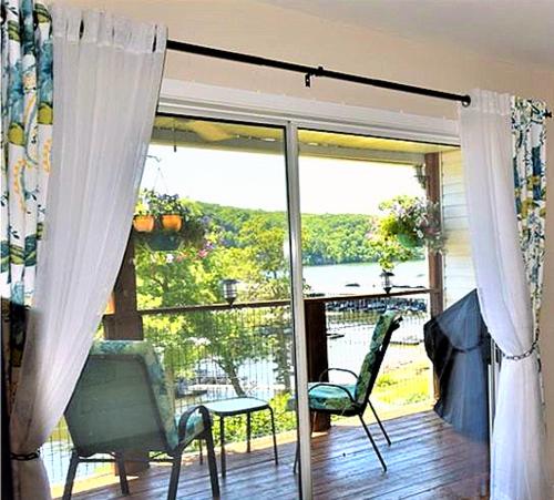 KaiserPeaceful 1st floor lakeside condo minutes from Osage Beach and Ozark State Park的客厅配有带椅子的滑动玻璃门