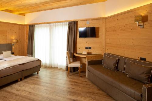 利维尼奥B&B Ecohotel Chalet des Alpes的酒店客房配有一张床、一张沙发和一张书桌。