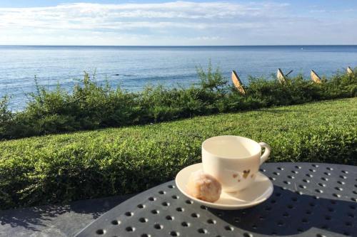 瓦尔纳Beach Villa Varna - cosiness 4 meters from the sea的一杯咖啡和一张在靠近海洋的桌子上的甜甜圈