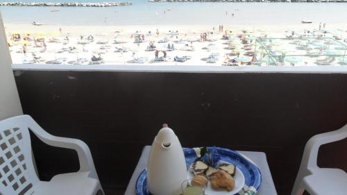 里米尼佐丹奴斯皮亚贾格酒店的一张桌子,上面放着一盘食物,享有海滩美景
