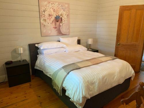 KilmoreDELIGHTFUL AND CHARMING ROSE COTTAGE的一间卧室配有一张带白色床单和绘画的床。