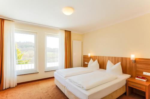巴特司塔福斯坦班泽尔瓦尔德贝格酒店的卧室设有一张白色大床和两个窗户。