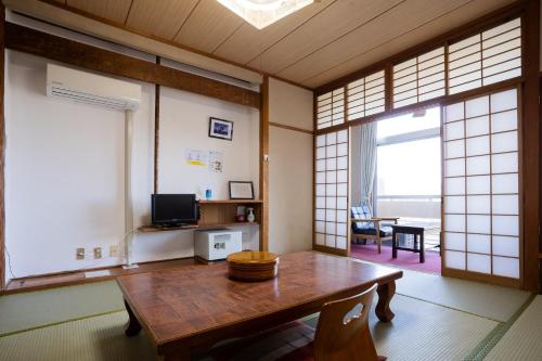 屋久岛屋久岛山莊酒店的带木桌的客房,位于带窗户的房间内