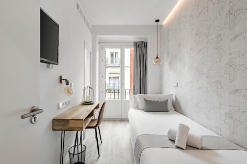 马德里Marco Polo Residence Hostal Boutique的白色的客房设有床、书桌和窗户。