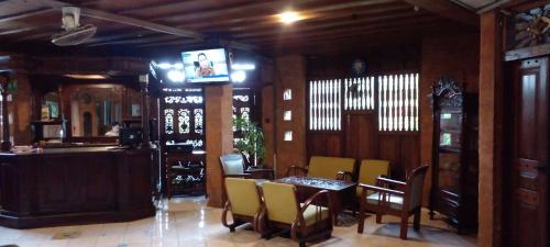 日惹Hotel Bifa Yogyakarta的一间带桌椅和电视的用餐室