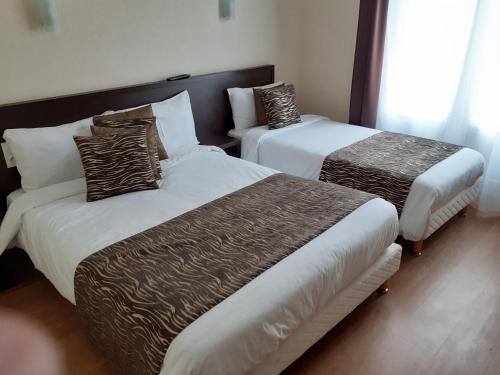 阿朗松乐查普罗格酒店的酒店客房带两张床,带棕色和白色的床单。