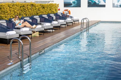 滨海卡涅Hotel Indigo Cagnes-sur-Mer, an IHG Hotel的坐在游泳池旁椅子上的女人