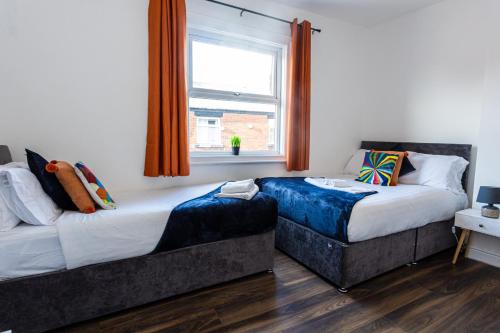 曼彻斯特M18 Abbey Hey Guesthouse的一间卧室设有两张床和窗户。