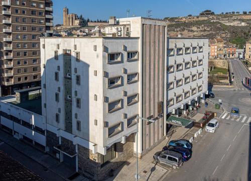 巴拉格尔HOTEL JAUME D'URGELL的一条高大的白色建筑,汽车停在街上