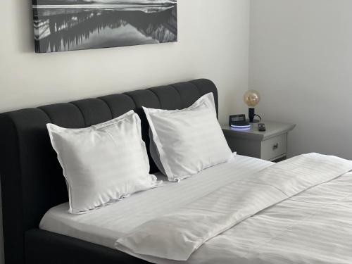 布拉索夫Maple Lodge Apartments的一张带白色枕头和黑色床头板的床