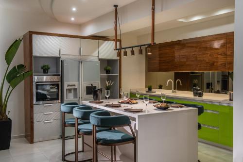 赫索尼索斯Maison De Mare, 4BR Central Luxury Beach Residence的一间设有绿色橱柜的厨房和一个带酒吧凳的白色岛屿