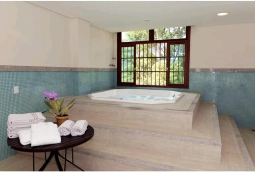 多明戈斯马丁斯SUÍTE EM PEDRA AZUL - Condomínio VISTA AZUL的带浴缸和毛巾桌的浴室