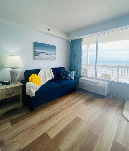 代托纳海滩Daytona Beach Resort Oceanfront CondoStudio的客厅设有蓝色的沙发和大窗户