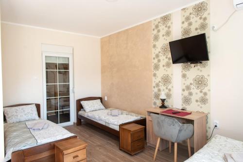 兹雷尼亚宁Zlatni Klas的客房设有两张床、一张桌子和一台电视机。
