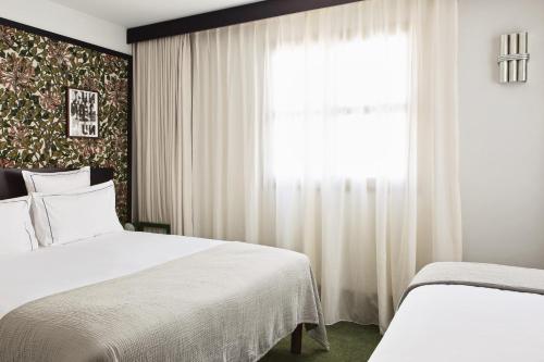 巴黎Hôtel Rosalie的一间卧室设有两张床和窗户。