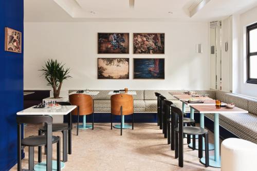 巴黎Hôtel Rosalie的用餐室配有桌椅和壁画