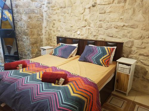 萨法德אורות בעתיקה - צימרים ונופש בצפת的一间卧室配有两张带彩色床单和枕头的床。