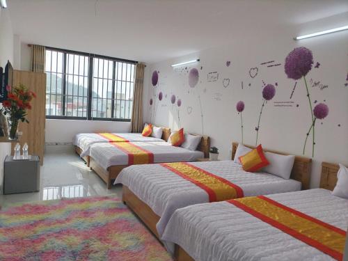 头顿Thảo Nguyên Hotel的一间设有三张床的客房,墙上挂着壁画