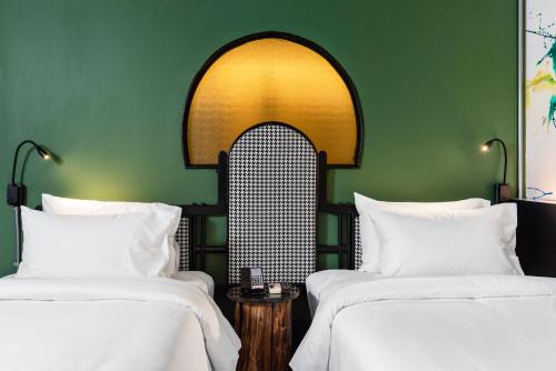 曼谷MeStyle Museum Hotel的绿墙客房内的两张床