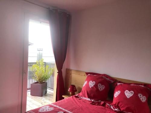 圣热尔韦莱班Charmant appartement的一间卧室配有一张带红色枕头的床和一扇窗户