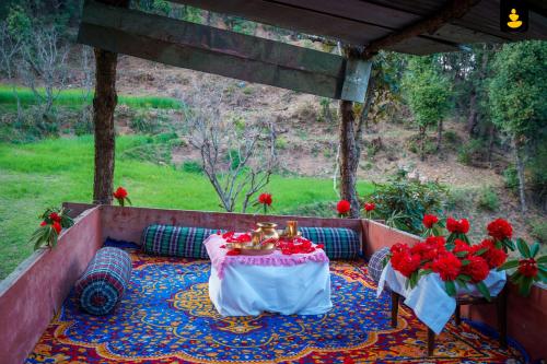 西姆拉LivingStone Shimla Jungle Stay的庭院里设有红色鲜花桌子