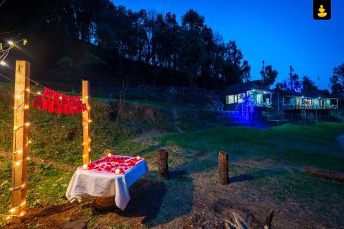 西姆拉LivingStone Shimla Jungle Stay的一张桌子,上面有红心,晚上在田野里
